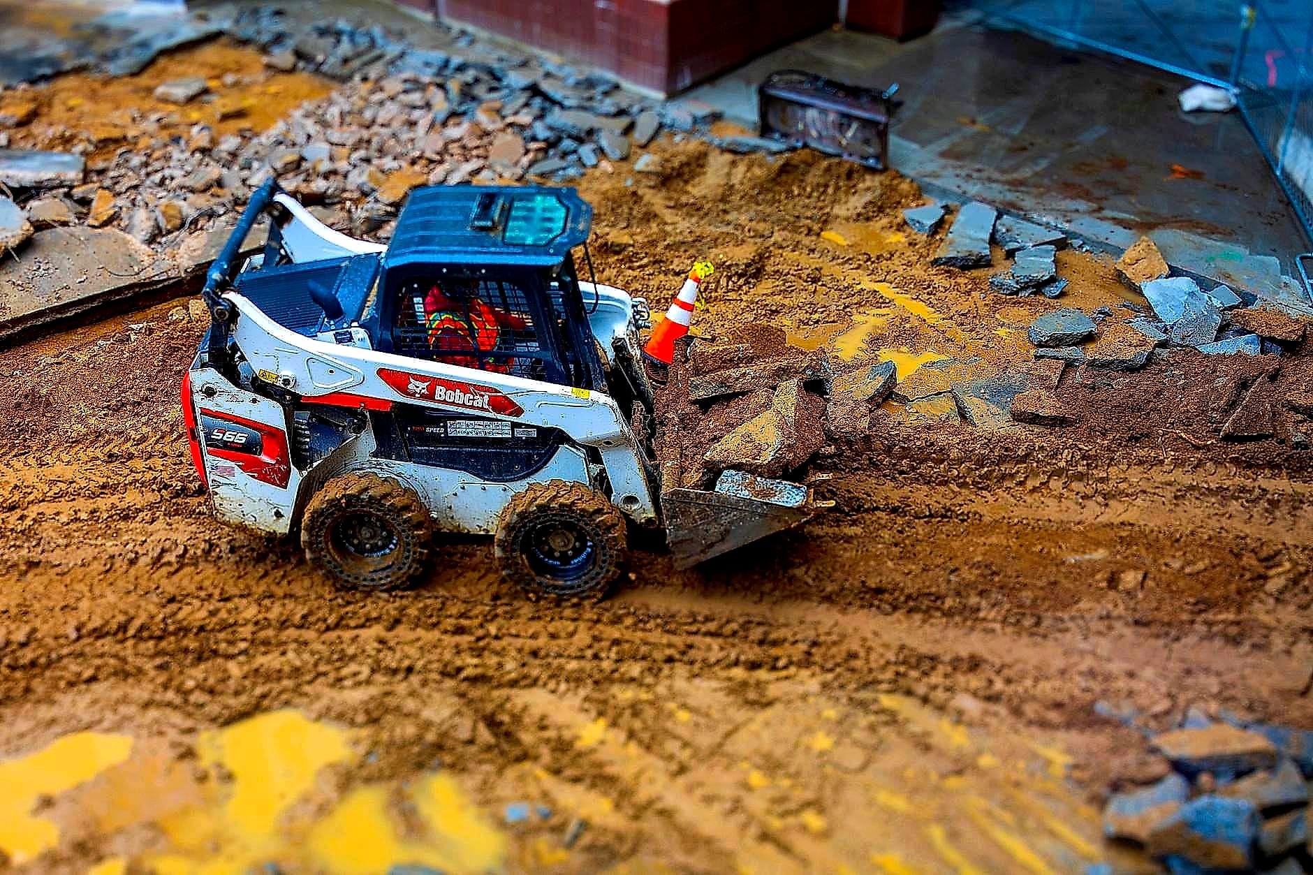 Skid steer loader moving material on a muddy site
